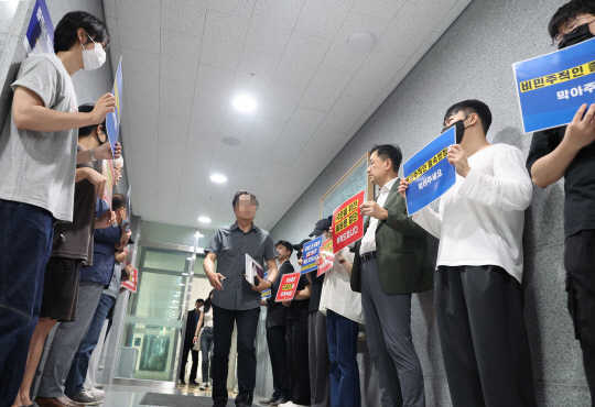 의대 증원을 담은 학칙 개정을 위한 전북대학교 교수평의회가 열린 22일, 의대 교수 및 학생들이 대학 본부 현관 앞에서 손팻말을 들고 의대 증원 반대를 촉구하고 있다.  [전주=연합뉴스]